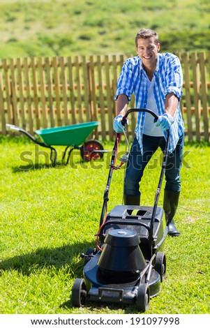 cheerful man lawn mowing in his home garden