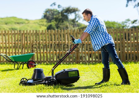 young man mowing lawn at home