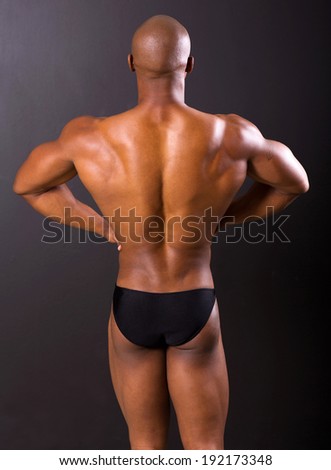 back view of african american bodybuilder isolated on black background