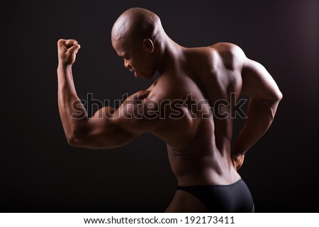 african american bodybuilder showing muscles on black background