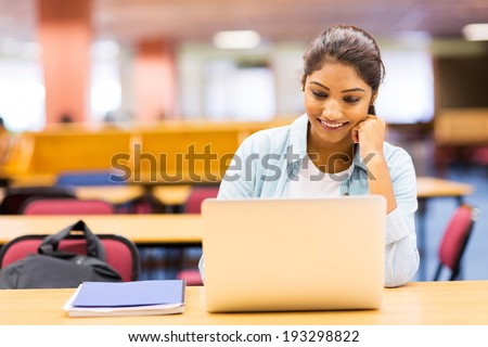female indian university student using laptop in lecture room