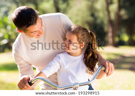 happy young father riding bicycle with his daughter outdoors