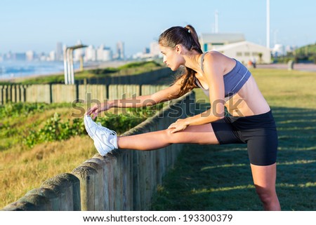 healthy woman stretching at the beach in the morning