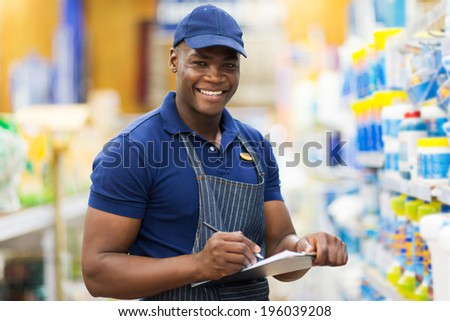 happy african shop assistant checking stock in supermarket