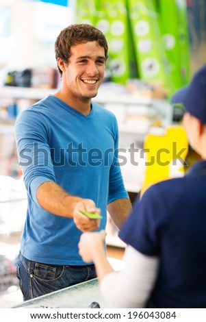 happy young man handing over credit card to a female cashier at till point