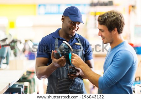 friendly hardware store worker showing customer a sander