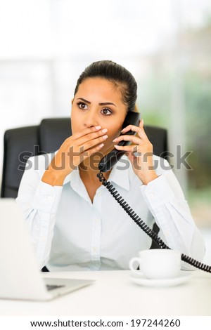 pretty young office worker receiving shocking news on the phone
