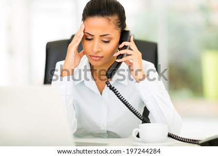 confused office worker talking on telephone in office