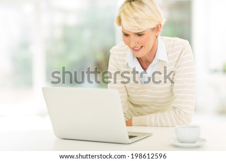 happy mid age woman using laptop computer at home