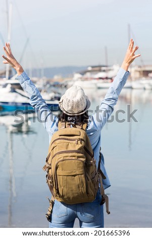 back view of female tourist with arms up at the harbor