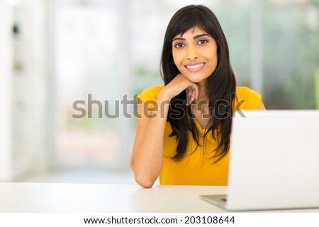 portrait of pretty indian woman sitting in front of laptop