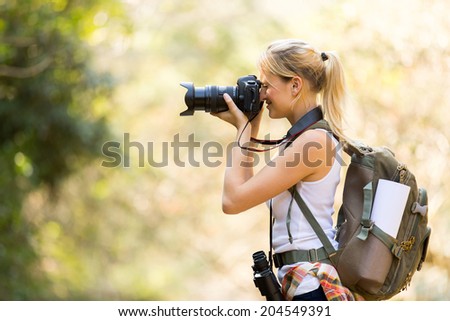 young female photographer taking photos in mountain valley