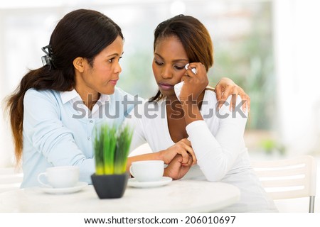 loving middle aged african woman comforting her sad daughter at home