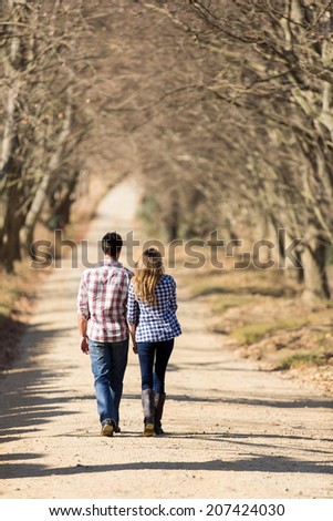back view of lovely young couple walking on country road in fall