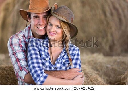 portrait of young cute farming couple hugging in barn