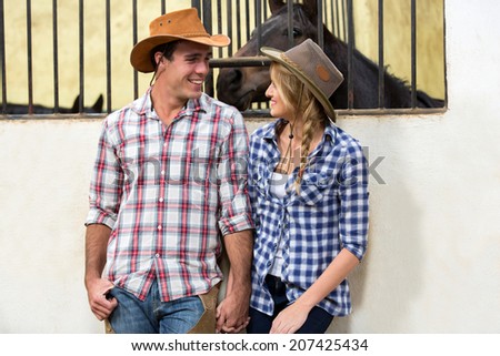 loving american western couple holding hands in stable