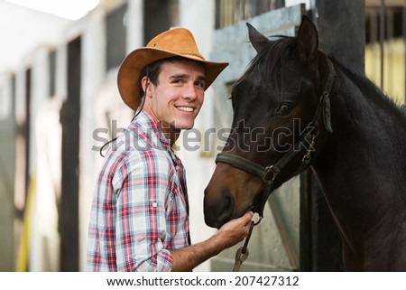 cheerful cowboy with a horse in stable