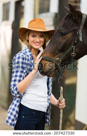 pretty cowgirl with her horse in stable