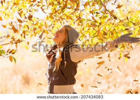 autumn leaves falling on happy young woman in forest