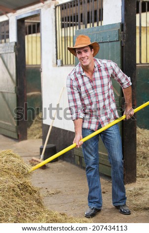 handsome young cowboy working in stable