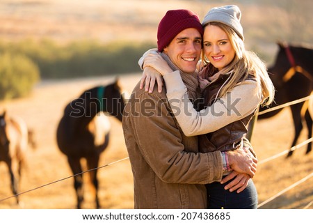 portrait of happy farm couple hugging in horse ranch