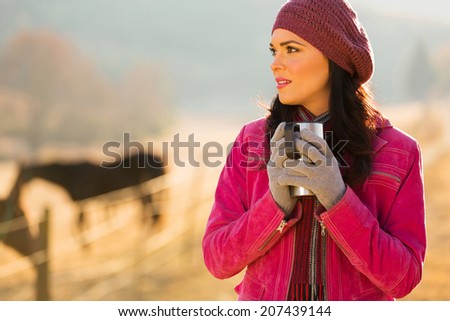 thoughtful woman in winter clothes holding hot drink outside