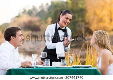 friendly female waitress taking order from cute young couple