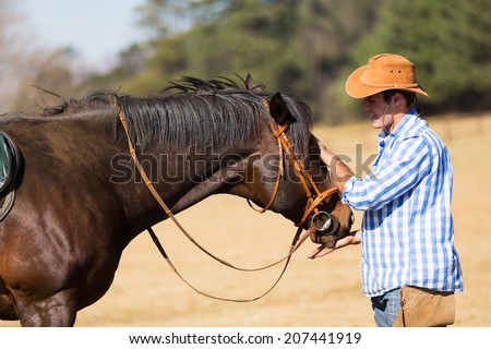 cowboy feeding his horse out of hand