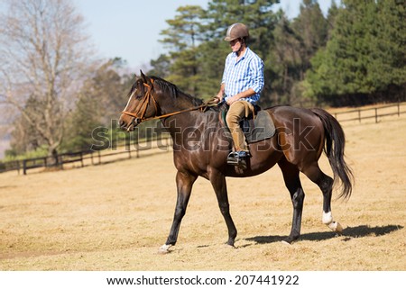 young man riding a horse in the field
