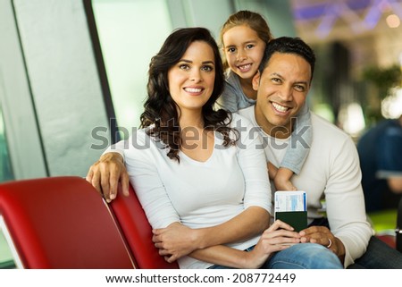 lovely young family looking at the camera while waiting for flight at airport