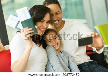 beautiful family taking selfie with smart phone while waiting for their flight at airport