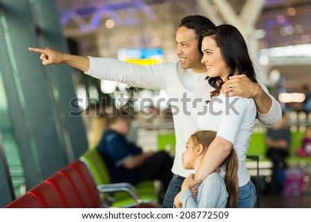 happy family standing at airport and pointing outside