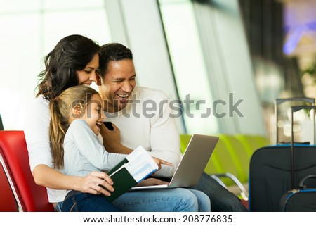 happy family of three using laptop computer at airport