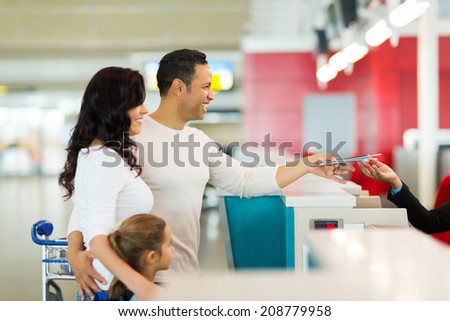 cheerful family handing over air ticket at airport at check in counter