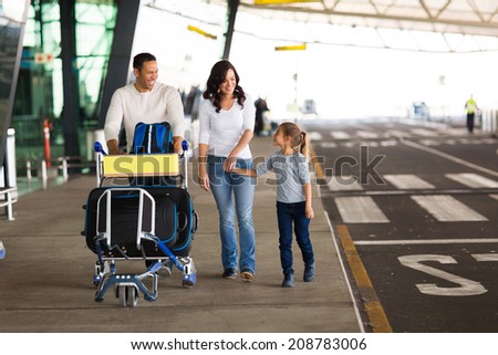 cheerful young family at airport with a trolley full of luggage