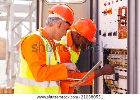 two experienced industrial technicians checking transformer