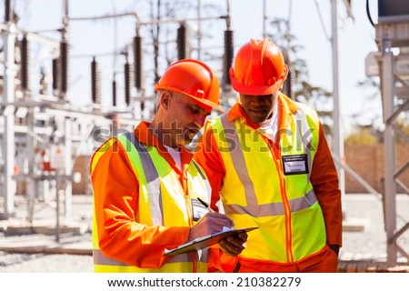 professional senior technician and electrical engineer writing on clipboard in substation
