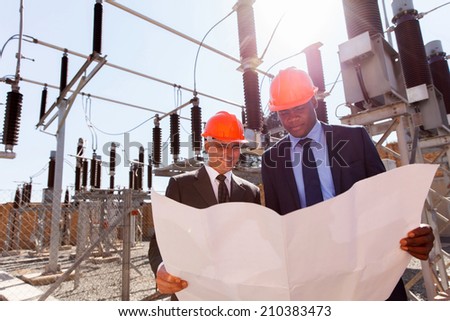 power company managers discussing blueprint at electrical substation