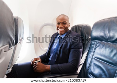 cheerful afro american businessman on board of an airplane during the flight
