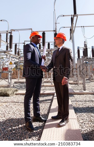 power company managers handshaking in electrical substation