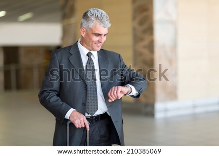 good looking mid age businessman checking time at airport