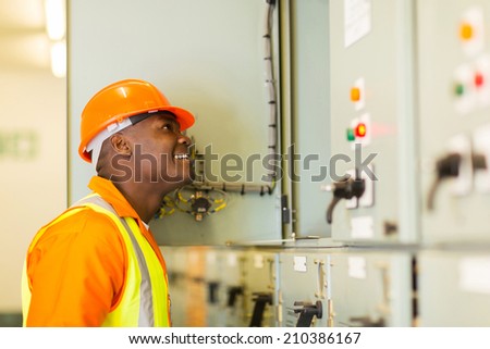 smiling young african american electrician looking at control room