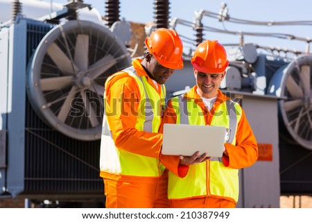 electrical engineers using laptop computer in electric substation