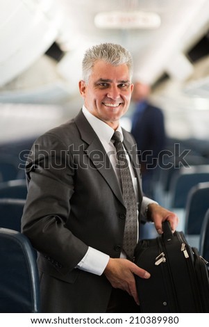 good looking middle aged businessman carrying bag on airplane