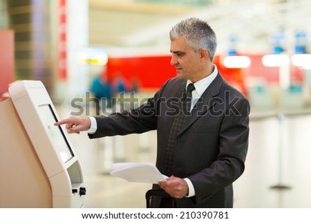 mid age business traveller using self help check in machine at airport
