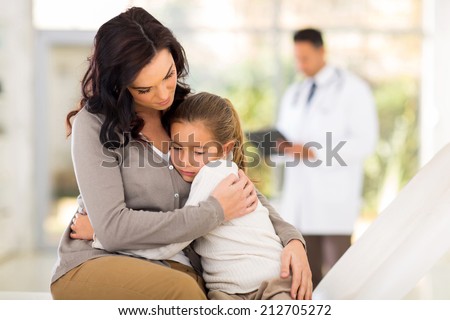sad young woman and her sick daughter waiting for checkup in doctor\'s room