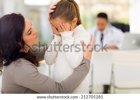 loving mother comforting her sick daughter in doctor\'s office