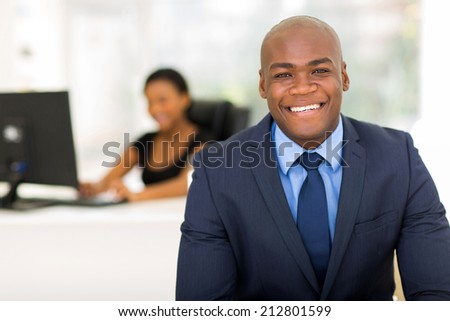 cheerful african american businessman in office with colleague on background