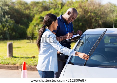 female african learner driver checking windscreen wiper during a driving test