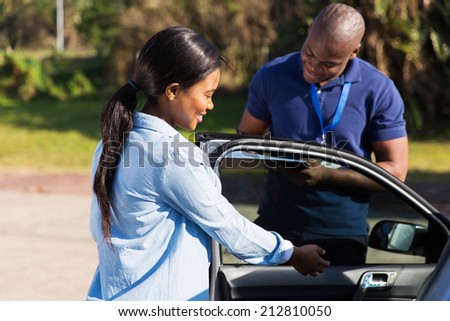 happy female african learner driver with instructor doing pre driving inspection